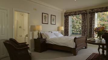 A bedroom with a large bed, two bedside tables with lamps, a chair, and a window with curtains.