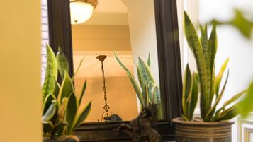 A wooden dresser with a mirror, a lamp, and two potted plants.