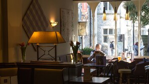 A restaurant interior with tables, chairs, a lamp, and a view of the street outside. - The Old Vine (Winchester)