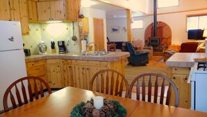 Eine geräumige Küche mit Holzausstattung, ein Essbereich mit Tisch für vier Personen und ein Wohnzimmer mit Kamin.