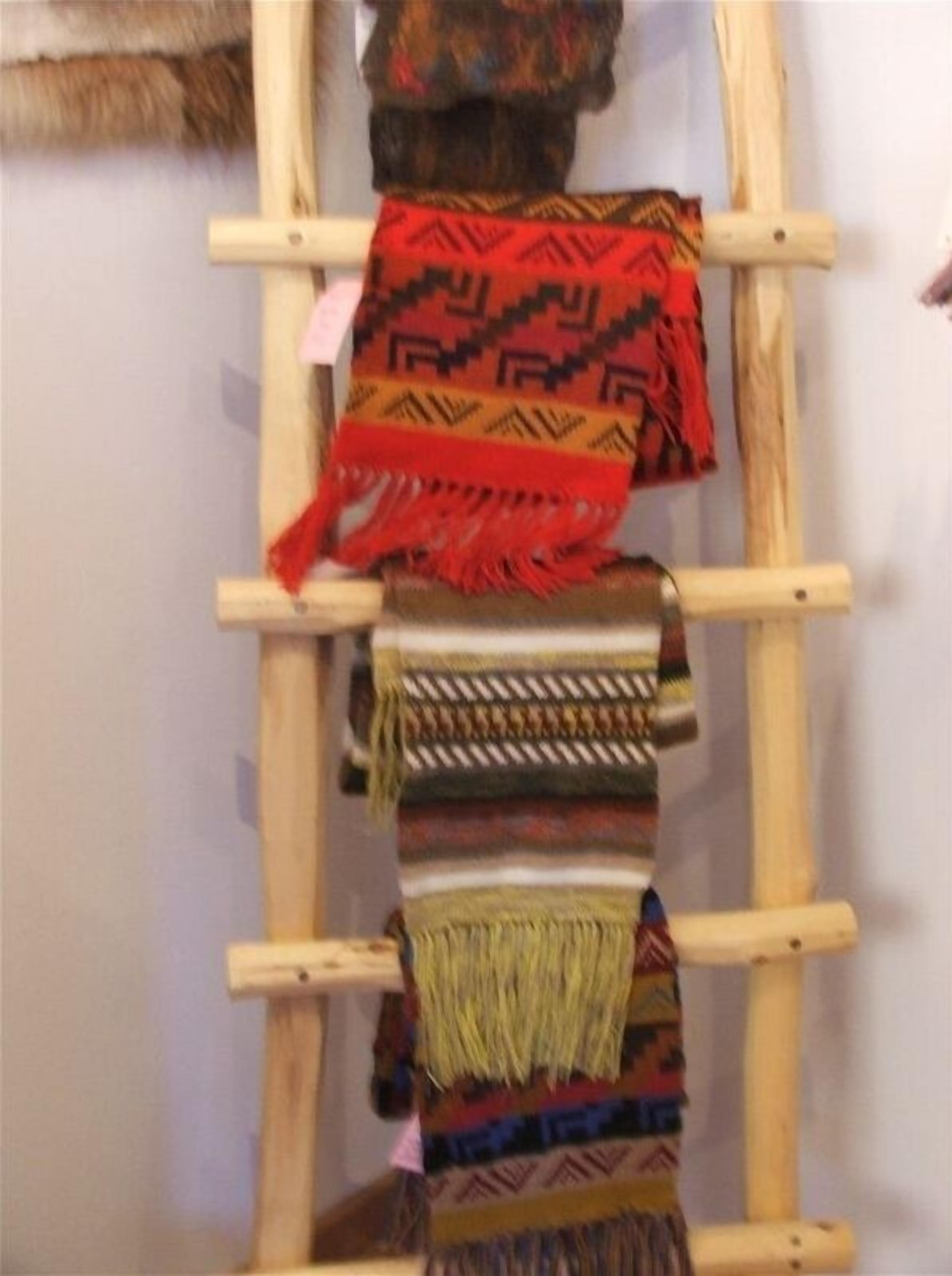 A wooden ladder with various woven textiles hanging on it.