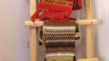 A wooden ladder with various woven textiles hanging on it.