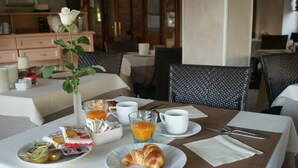 A breakfast setting with a croissant, juice, and pastries on a table. - Hotel Michela (Massa)