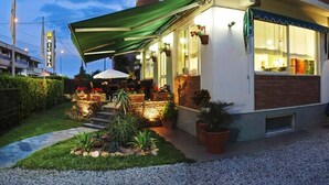 A hotel with outdoor seating, a green awning, and potted plants. - Hotel Michela (Massa)