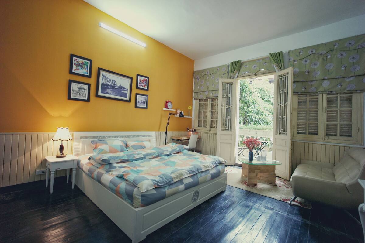 A bedroom with a bed, bedside table, lamp, and a window with curtains.