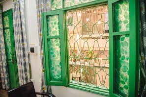 A room with a green-framed window, a chair, and a table with a potted plant. - Hanah's Tiny Hanoi Homestay (Hanoi)