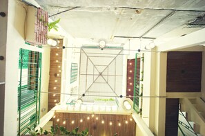 A multi-level atrium with a central staircase, wooden paneling, and string lights. - Hanah's Tiny Hanoi Homestay (Hanoi)