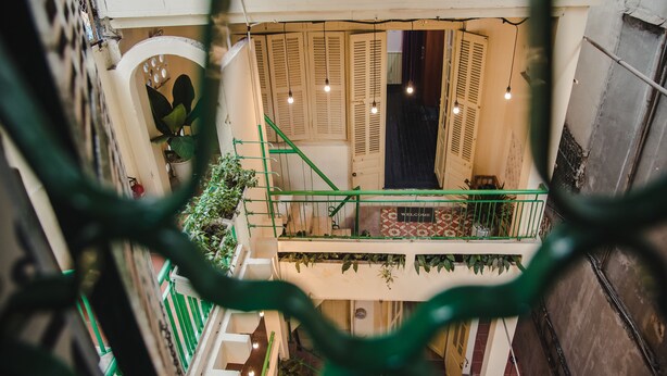 Ein mehrgeschossiges Interieur mit einer Treppe, Holztüren und hängenden Lampen.