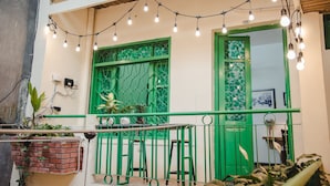 Ein Balkon mit grünen Geländern, Blumentöpfen und Lichterketten.