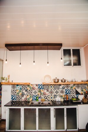 Una cocina con salpicadero de azulejos, luces colgantes y armarios.
