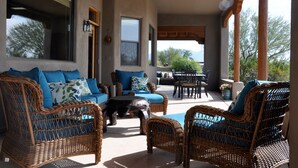 Eine Terrassensitzgelegenheit mit Korbmöbeln, einem Tisch und Blick auf die umliegende Landschaft.
