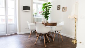 A dining area with a round table, white chairs, a potted plant, and a floor lamp. - Alessia's Place (Como)