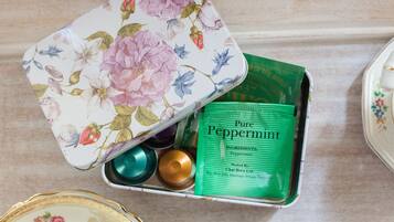 A floral-patterned tin box containing a green packet labeled "Pure Peppermint" and a few small containers.