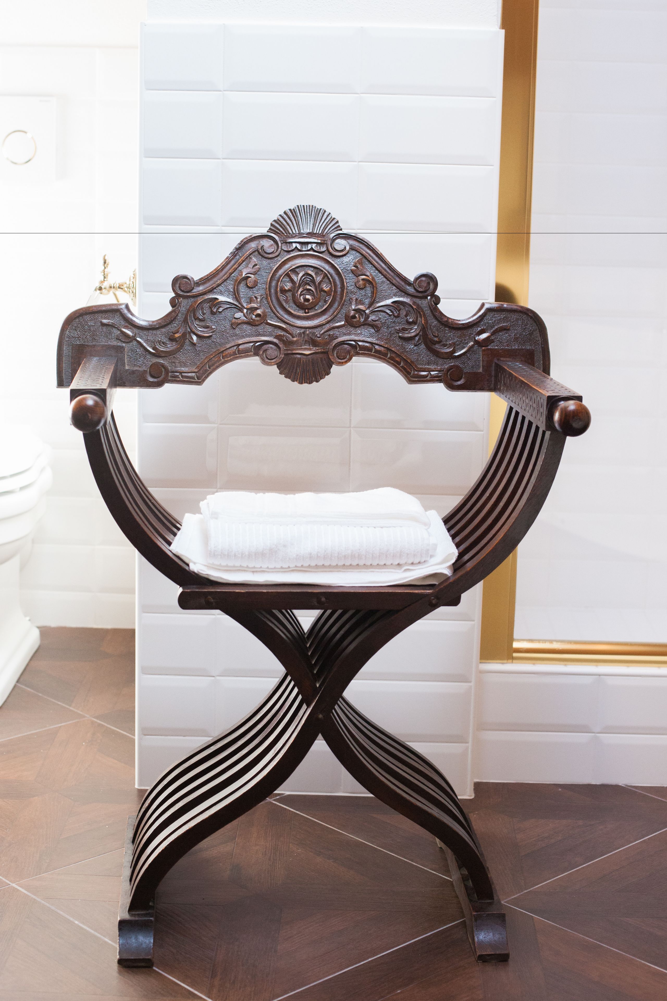 Un banc en bois doté d’un dossier décoratif et sur lequel est posée une serviette.