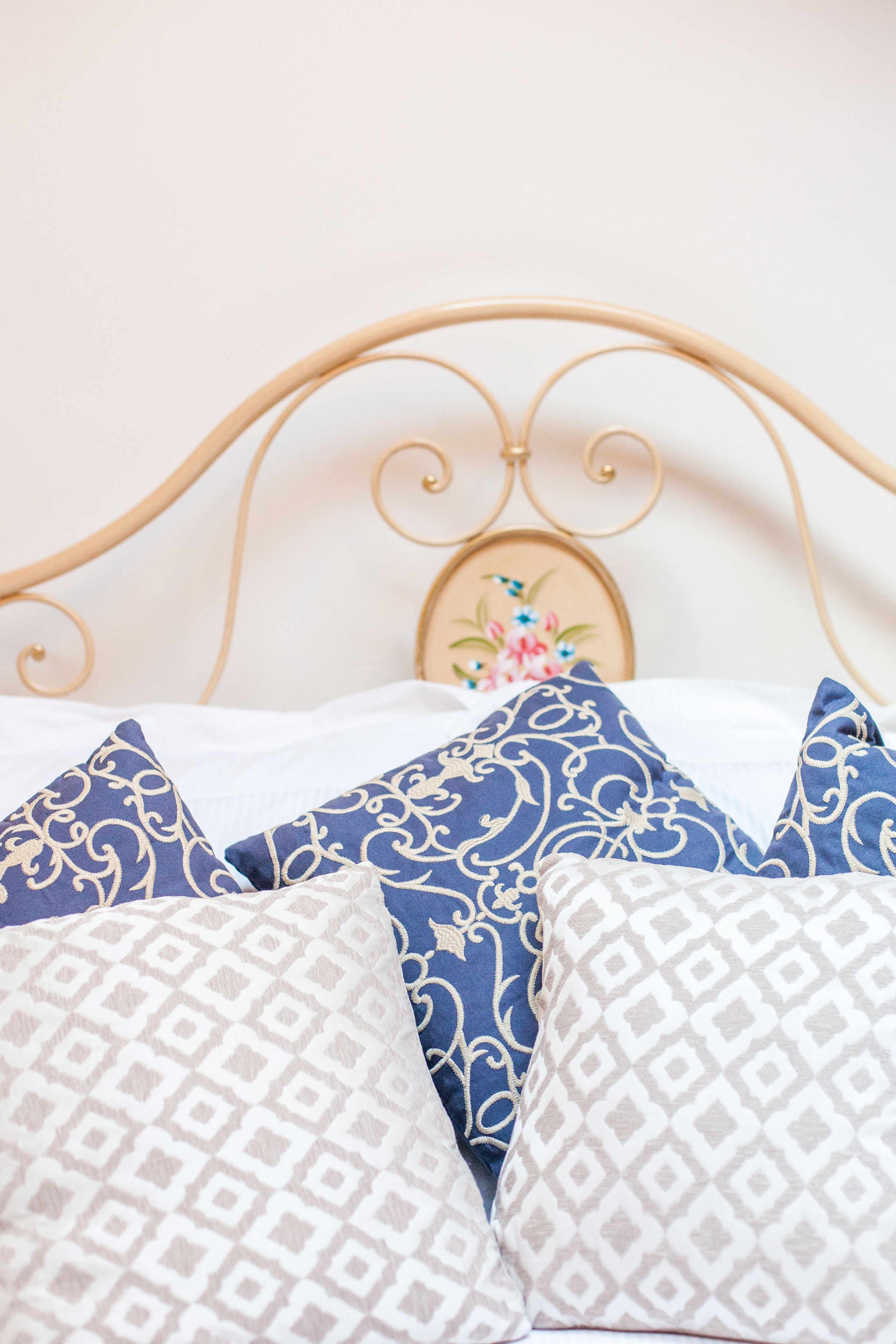 A bed with a metal headboard and decorative pillows.