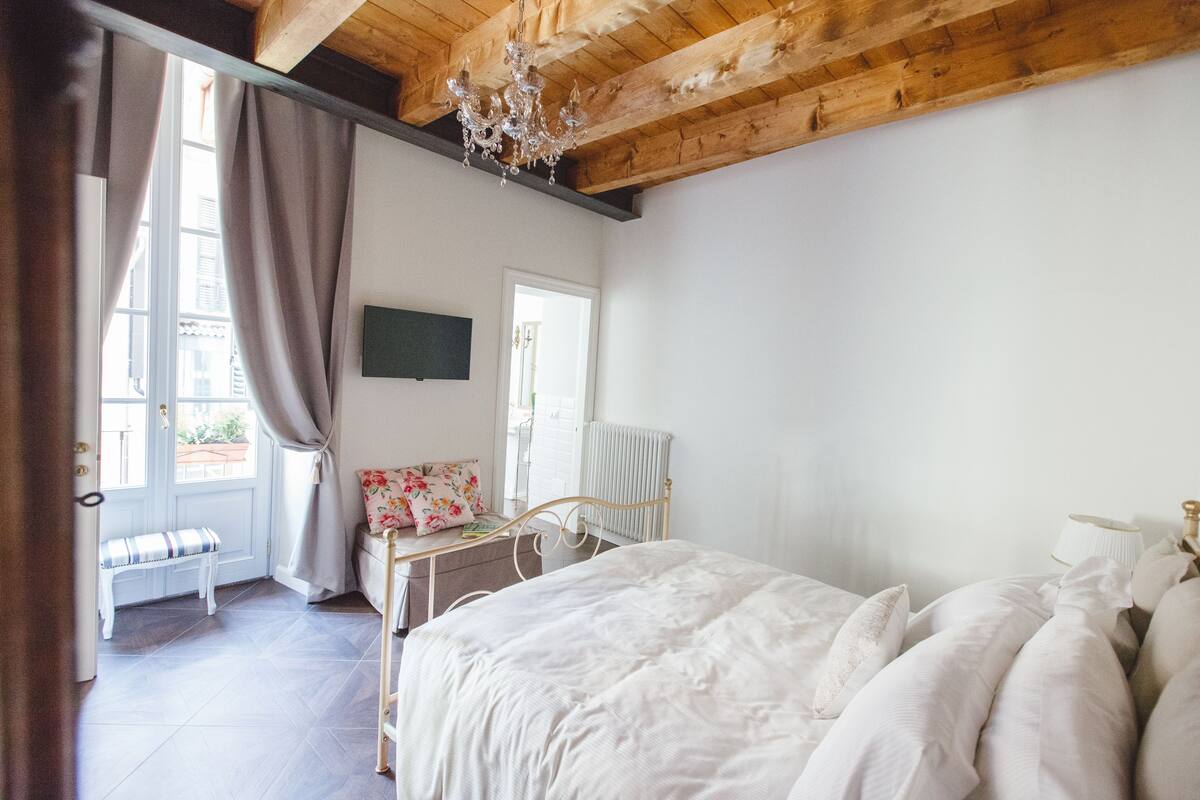 A bedroom with a bed, a bench, a radiator, and a chandelier.