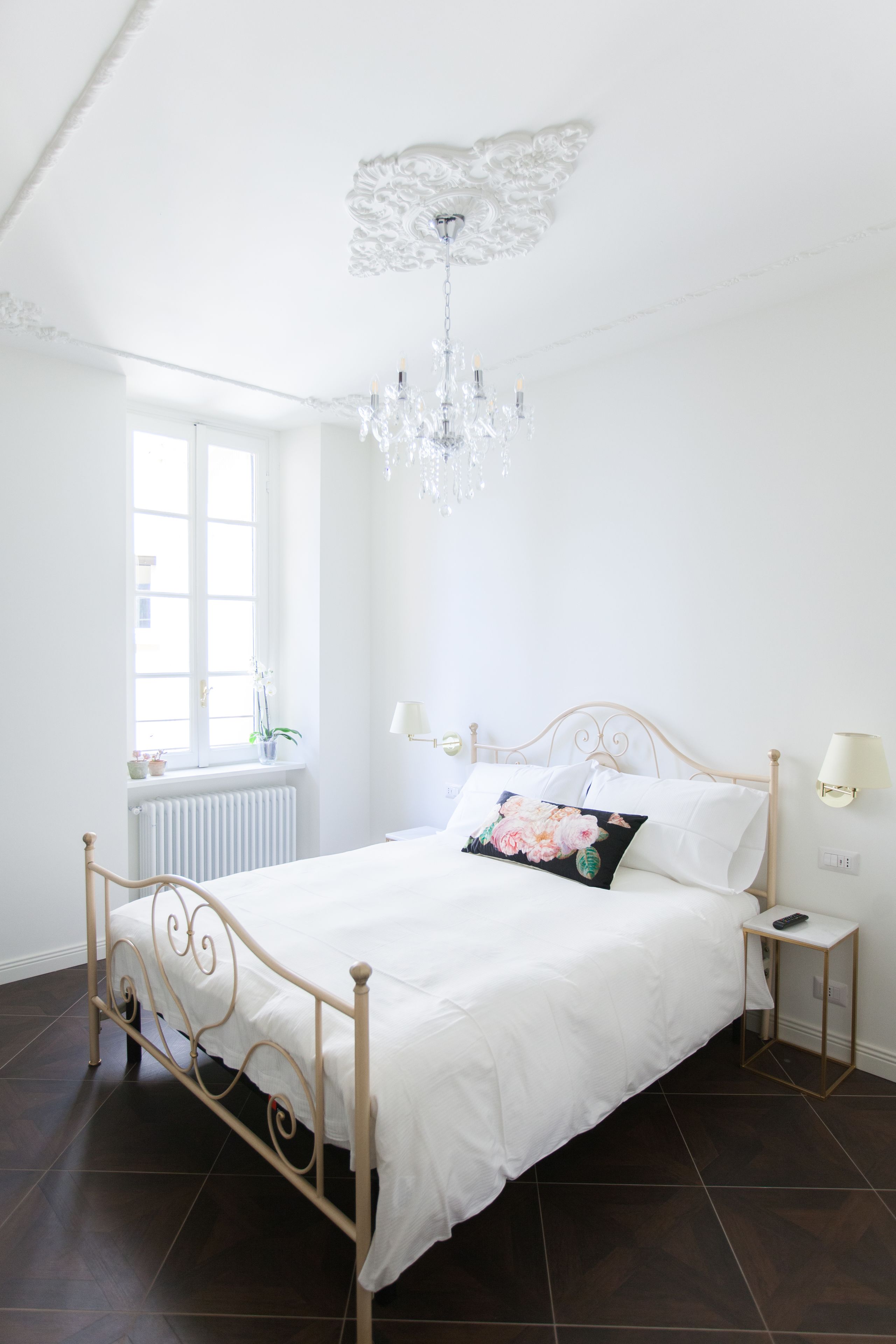 Ein Schlafzimmer mit einem weißen Bett, einer Deckenleuchte, einem Fenster mit Blick und einer Heizung.