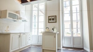 A kitchen with white cabinetry, a microwave, and a window with shutters. - Alessia's Place (Como)