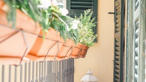 A narrow alleyway with a metal fence, a hanging flower pot, and a lantern on the ground. - Alessia's Place (Como)
