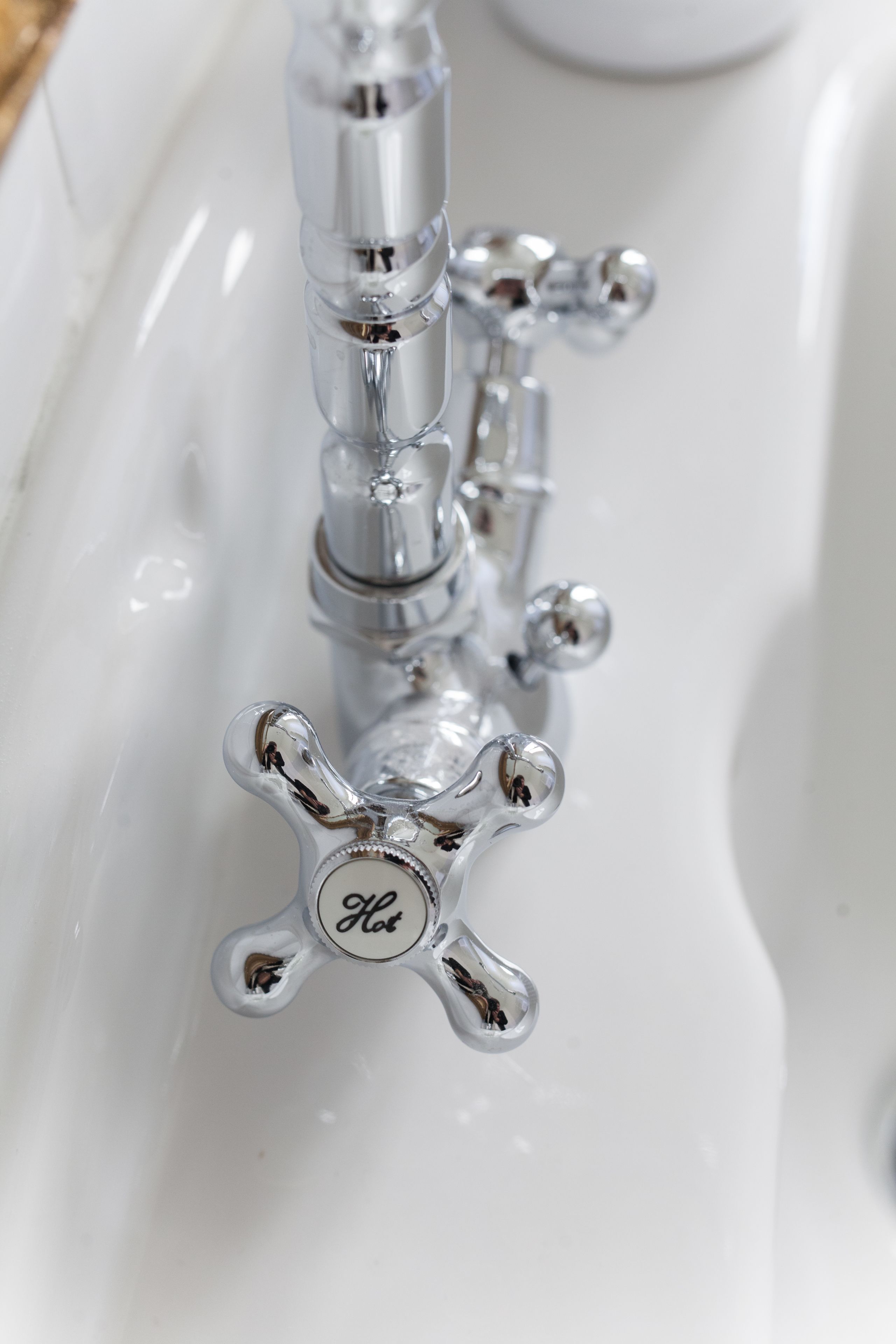 A close-up of a chrome faucet with a 'Hot' label on a white sink.