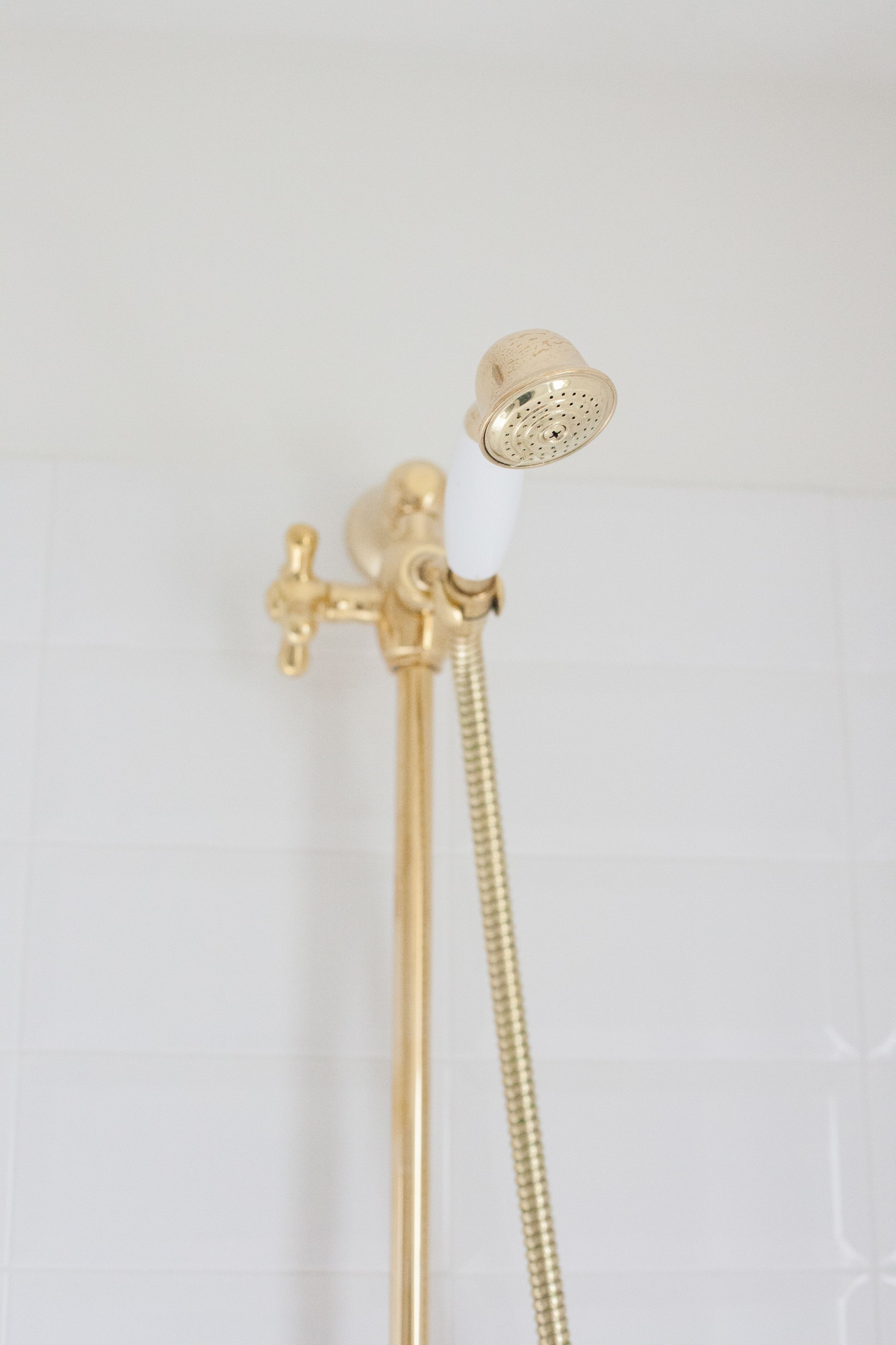 A gold showerhead with a white hose attached to a gold faucet.