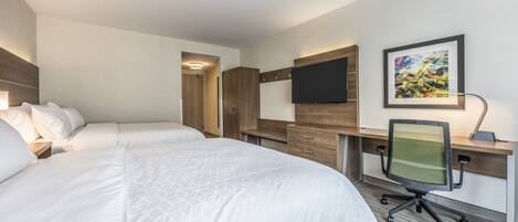 A hotel room with a large bed, a desk with a chair, a flat-screen TV, and a framed picture on the wall.