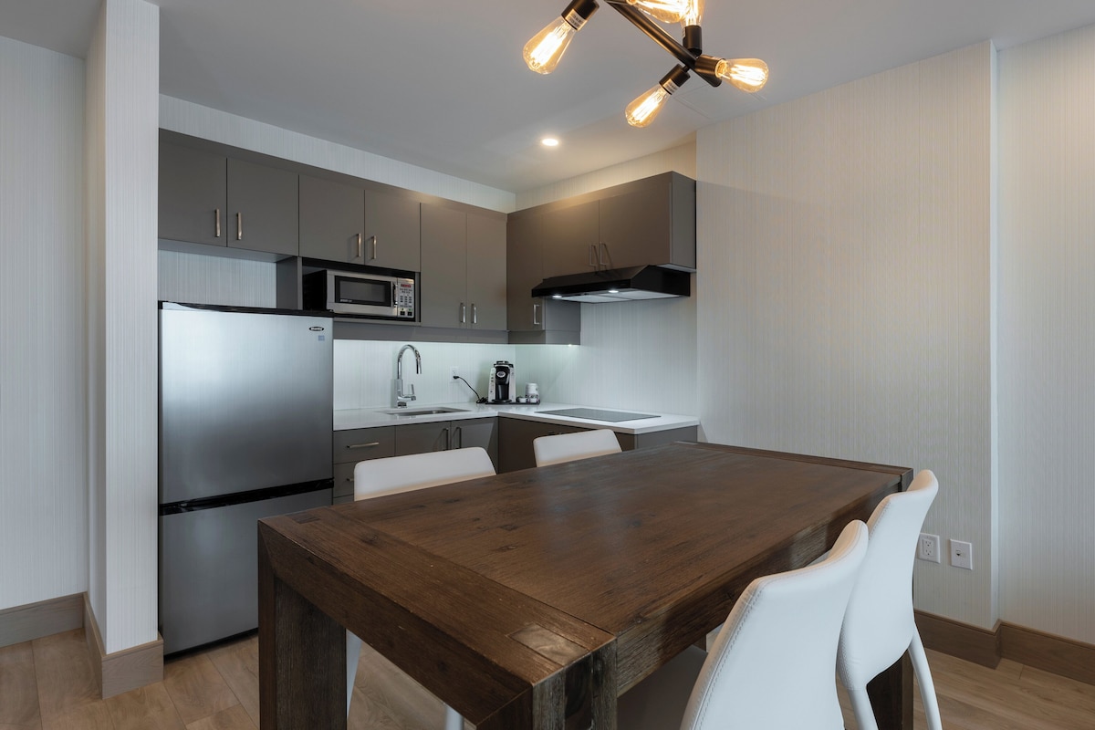 A modern kitchen with a wooden dining table and white chairs.
