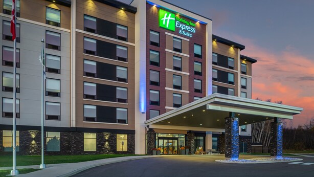 Un hotel Holiday Inn Express & Suites amb un disseny modern, que destaca per una entrada coberta i una senyalització ben visible.