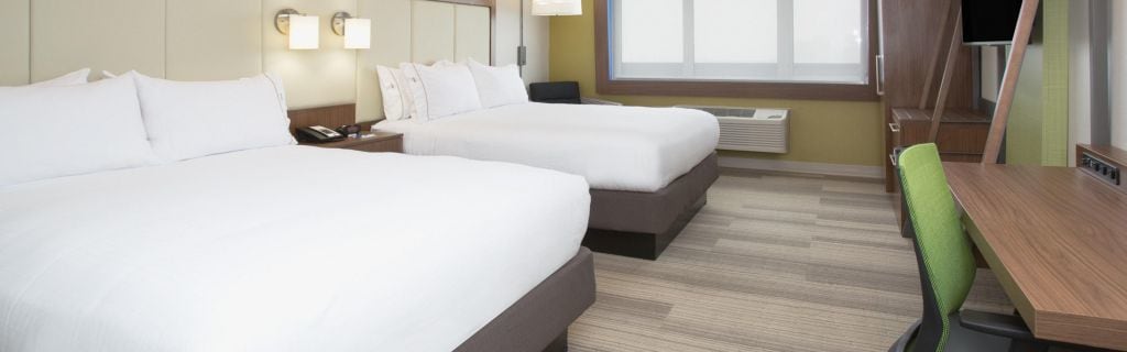 Une chambre d’hôtel avec deux lits, un bureau, une chaise et un téléviseur.