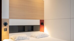 Une chambre à coucher moderne avec un grand lit, une tête de lit intégrée, un éclairage de chevet et une armoire.