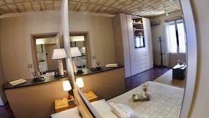 Una habitación de hotel con una cama, mesitas de noche, un escritorio, un espejo y un armario.