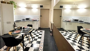 Una cocina compacta con armarios blancos, piso a cuadros blanco y negro, y una isla central.