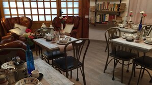 A cozy dining area with wooden tables and chairs, a leather sofa, and a bookshelf filled with books. - City View Pescara (Pescara)