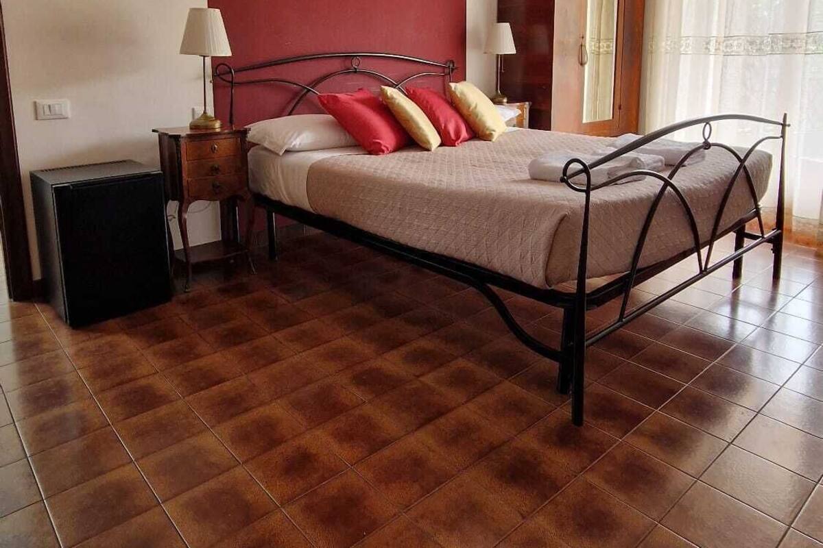 A bedroom with a bed, a nightstand, a lamp, a dresser, and a chandelier.