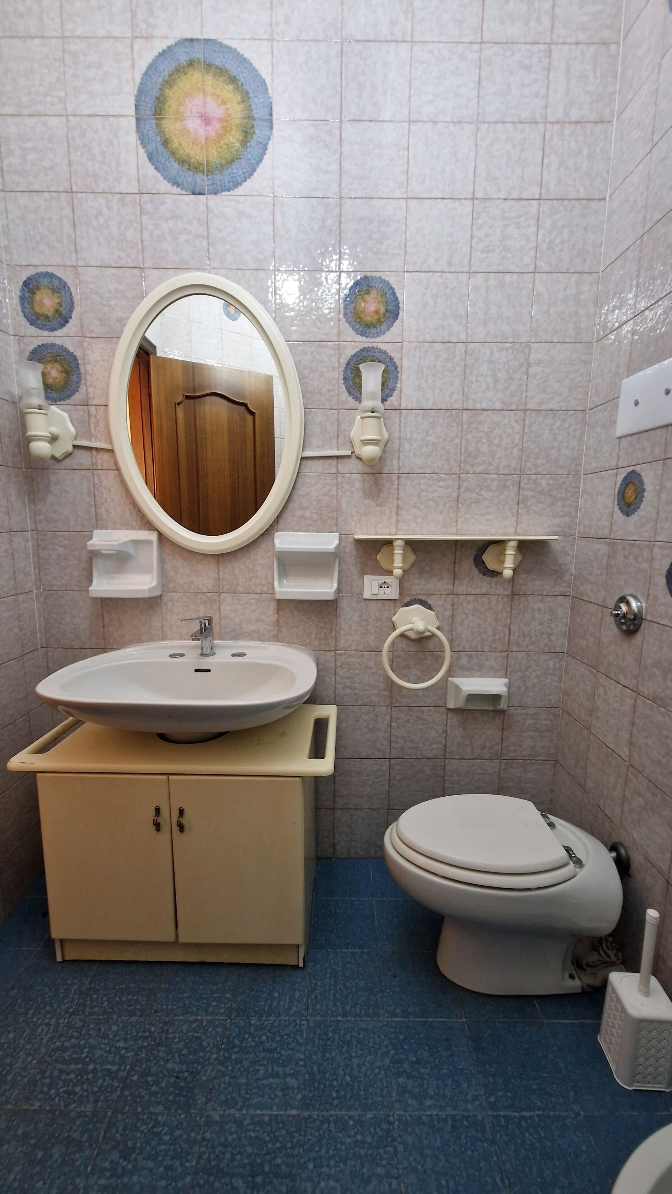 A bathroom with a sink, mirror, toilet, and decorative tiles.