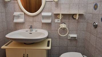 A bathroom with a sink, mirror, toilet, and decorative tiles.