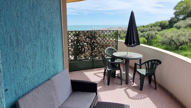 A covered outdoor seating area with a sofa, chairs, and a table, overlooking a scenic landscape. - City View Pescara (Pescara)