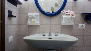 A bathroom with a white sink, a mirror, and a towel rack with a flower.