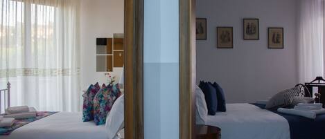 A hotel room with two beds, a mirror, a chandelier, and artwork on the wall.