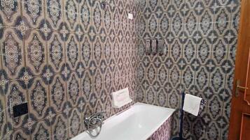 Un bany amb rajoles decorades, una banyera, un lavabo i un vàter.
