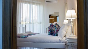 A hotel room with a bed, a nightstand with a lamp, a mirror, and an air conditioning unit. - City View Pescara (Pescara)