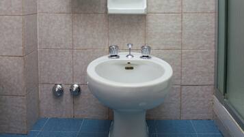 A bathroom with a white pedestal sink, two faucets, and a blue floor.