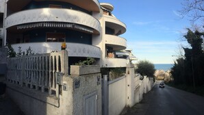A multi-story residential building with balconies, a gated entrance, and a clear view of the sea in the background. - City View Pescara (Pescara)