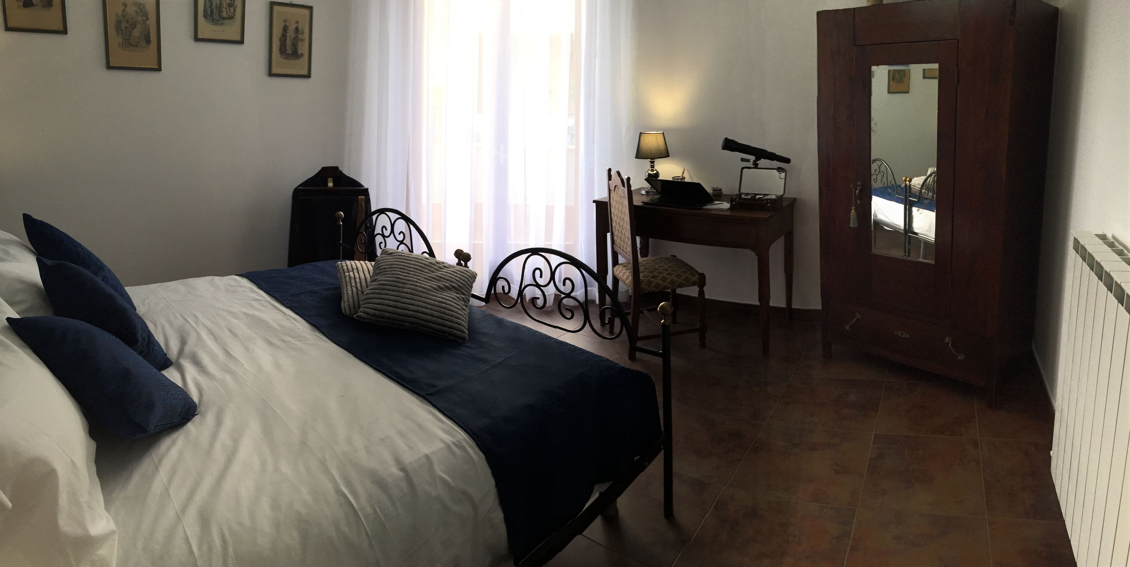 Un dormitorio con cama, escritorio, silla, lámpara y espejo.