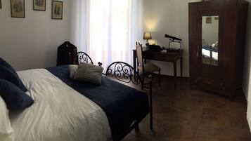 Un dormitorio con cama, escritorio, silla, lámpara y espejo.
