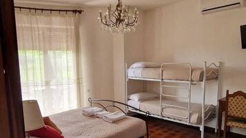 A room with a bunk bed, a chandelier, a window with curtains, and an air conditioning unit.