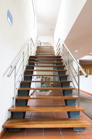 A modern staircase with wooden steps and metal railings, leading to a landing area with a white wall and a blue sign. - Hotel Rural Santo António (Arronches)