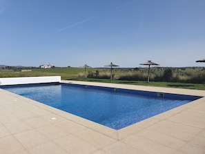 Una piscina al aire libre de temporada, sombrillas