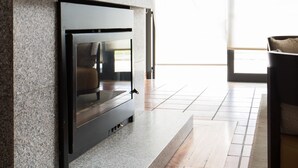 A modern interior with a built-in fireplace, a wooden floor, and a large window. - Hotel Rural Santo António (Arronches)