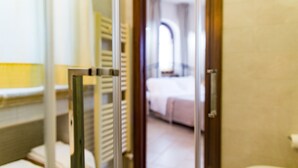 Una habitación de hotel con una cama, un baño y una puerta de vidrio que da a otra habitación.